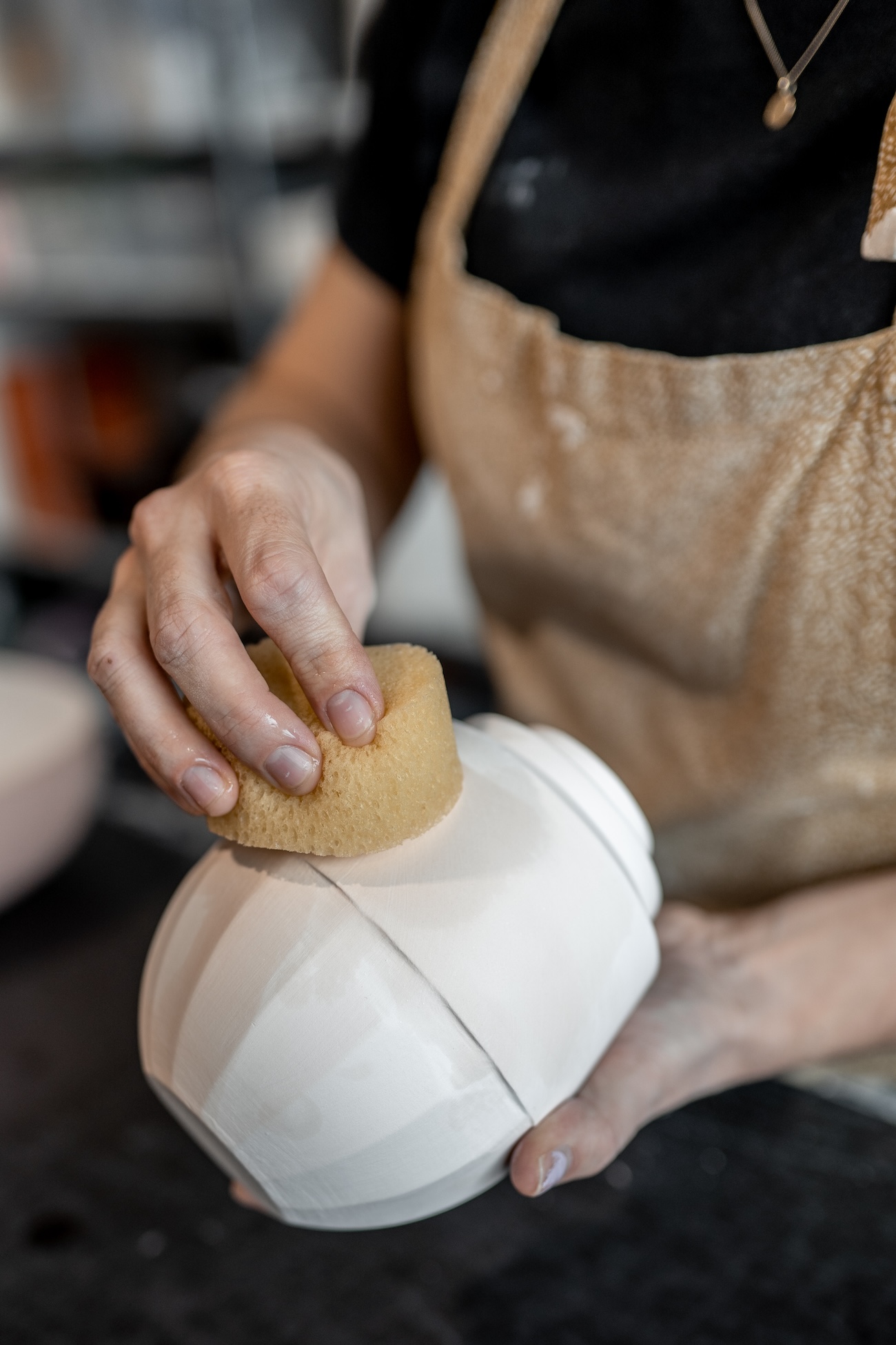gegoten porseleinen urn wordt afgewerkt met een spons.