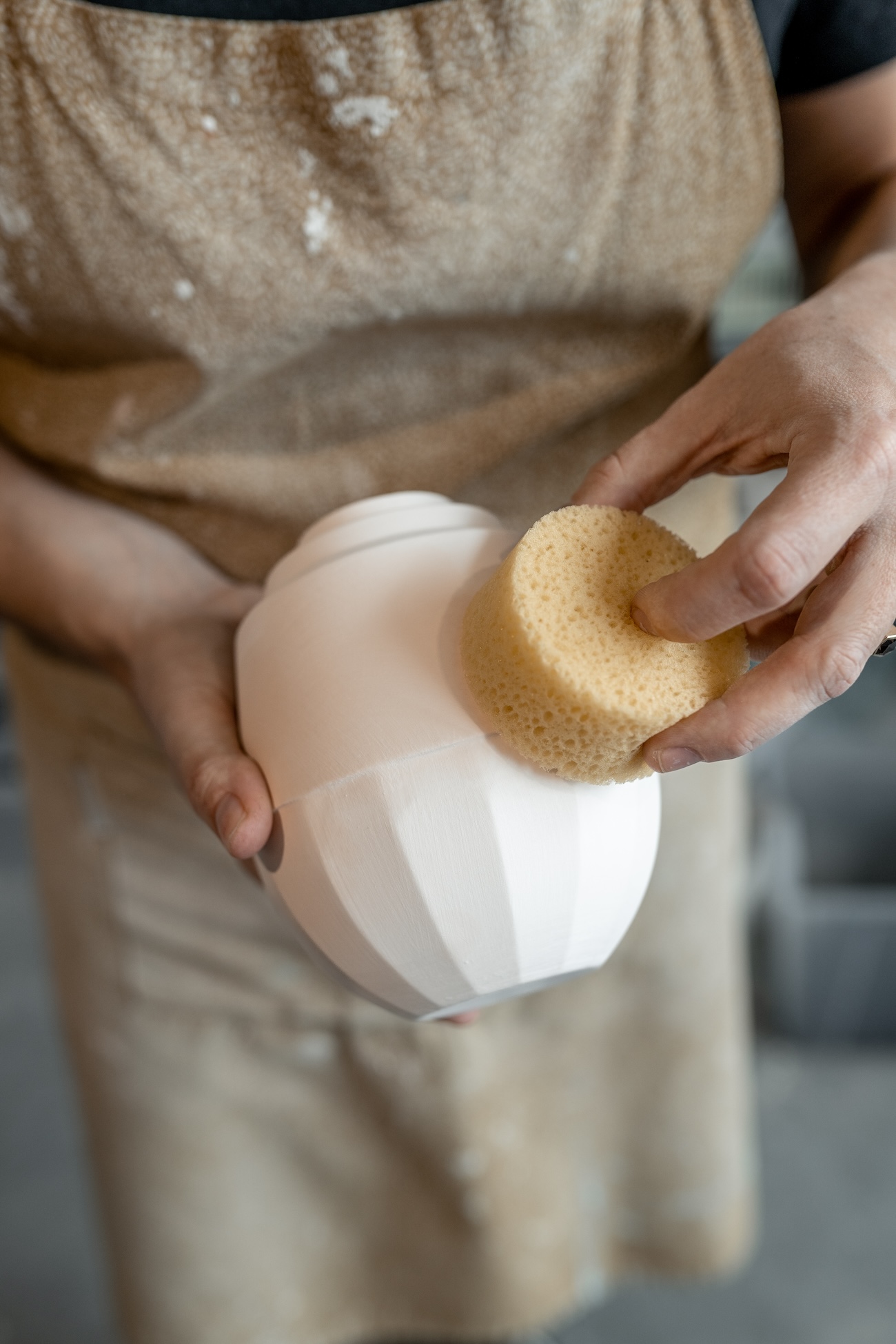 gegoten porseleinen urn wordt afgewerkt met een spons.