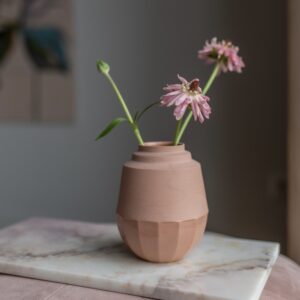 Klein vaasje gemaakt van porselein in een terra kleur. Vaasje heeft een strak design en is deels mat en deels geglazuurd.