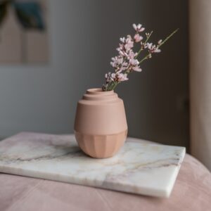 klein vaasje handgemaakt van porselein in de kleur terra. Het vaasje is gevuld met kleine bloemetjes