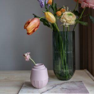 klein roze vaasje gemaakt van porselein. Naast het vaasje staat een grote glazen vaas van HAY