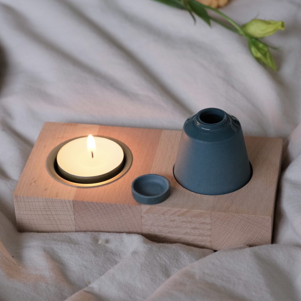 houtenplankje met daarin een klein keramiek urntje en waxinelichtje.